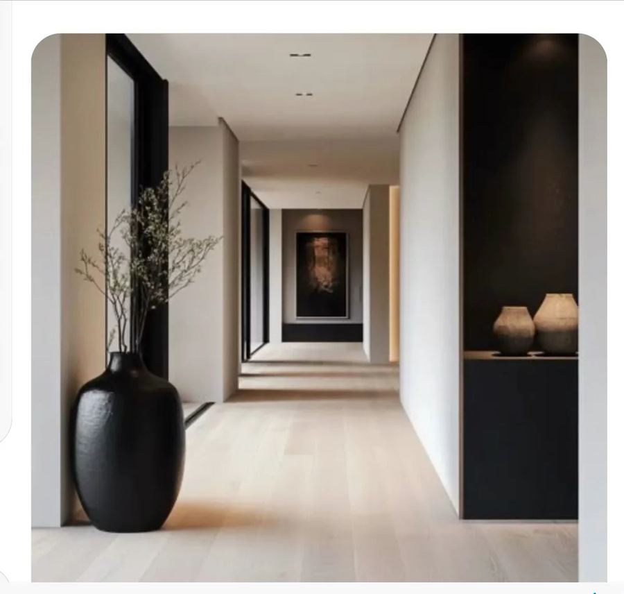 Long modern corridor with light oak floor and a tall recessed wall niche on the right side painted in dark charcoal containing two ceramic vases